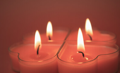 Four red burning heart-shaped candles with blazing flames. Tongues of fire on a red background. Valentine's Day, passion, love, feelings concept. Monochrome wallpaper. I love you decor for February 14