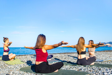 group of young females practicing yoga on the seaside