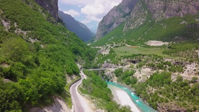 Winding road alongside a blue river in the beautiful Valbona Kukes of the Albanian Alps, Eastern Europe. Aerial flyover