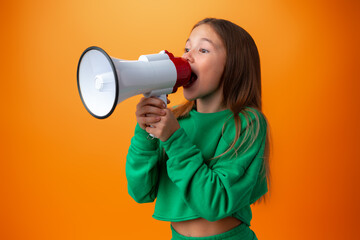 Teen girl making announcement with megaphone against orange background