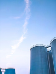 Low angle view of storage fuel tanks inside of petroleum industrial area against blue sky in evening time