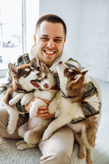 guy growls at the camera and shows his teeth. european man holding a lot of husky puppies in his...