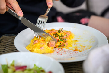 A knife and fork being used to cut up an omelette