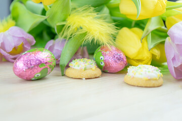 Wielkanocna, wiosenna aranżacja, tulipany, piórka, ciastka, kolorowe jajka, tło z miejscem na...