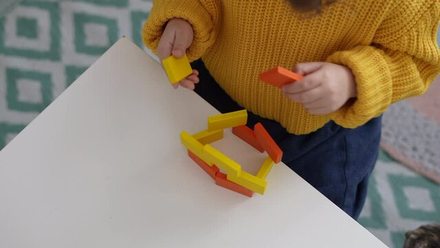 Close up view hands of preschooler playing with wooden blocks. Homeshooling. Learning Community. Montessori School