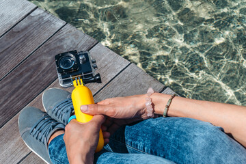 Action camera in the hands of a girl. Against the backdrop of a wooden deck, a tabletop on the surface of the water against the background of the pool.
