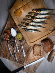 Cold smoked fish on an old wooden board with spices.