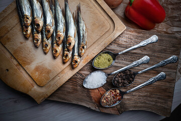 Cold smoked fish on an old wooden board with spices.