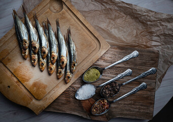 Cold smoked fish on an old wooden board with spices.