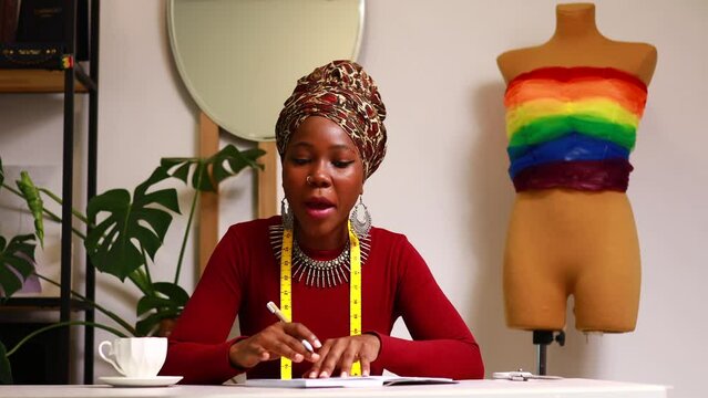 tanzanian woman with snake print turban over hear creating a colorful dress for pride parade in her dressmaking showroom