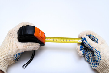 Hands of a worker, builder in protective gloves halding a ruler, using tape measure against white background
