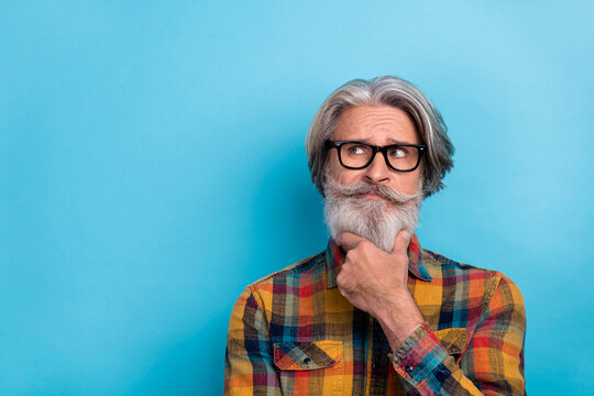Photo of aged man hand touch chin think deep ponder look empty space smart isolated over blue color background