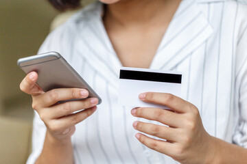 Female hands holding a credit card and using smartphone. Concept of online shopping. Online payment.
