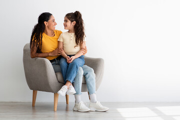 Happy Family Of Two Mother And Daughter Relaxing In Chair At Home