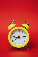 Bright yellow retro alarm clock isolated on paper red background. Time, minutes, hours concept. The value of time in business and life. Clock showing nine hours 15 minutes. Vertical photography.