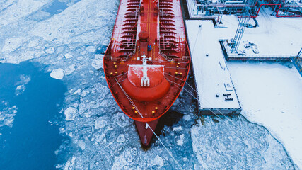 Oil shipment on big red tanker from terminal pumping system on water covered with thick layer of broken ice in frosty winter aerial view © wifesun