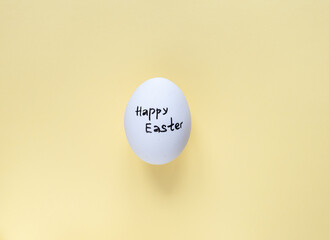 Easter concept. An egg with an inscription on a yellow background. Easter layout. A postcard for Easter. Pastel background. location of the top view