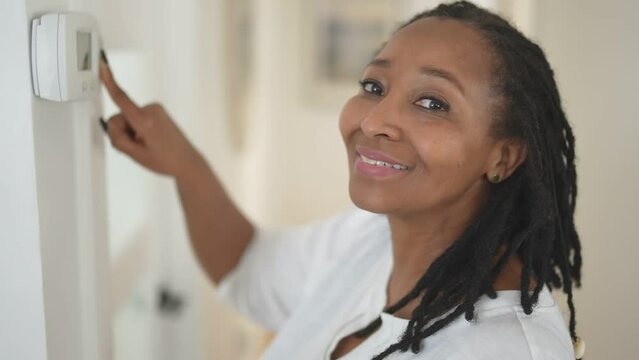 A African Woman Lady Adjusting The Climate Control Panel On The Wall Wall Thermostat