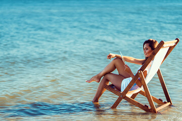 Beautiful woman relaxing a deckchair on a seaside. Summer vacation. Travel agency