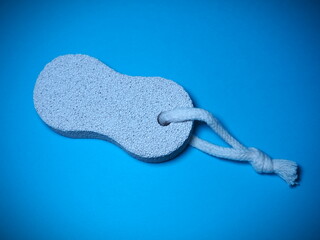 Bathroom spa foot scrubber for removing dead skin isolated on blue background. Pumice stone with...