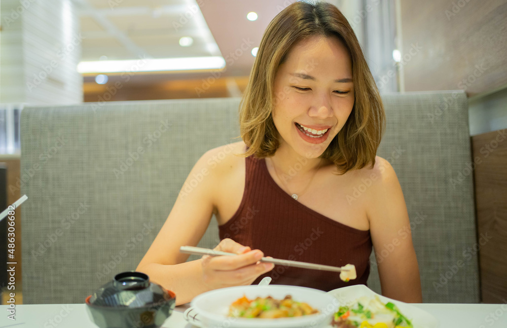 Wall mural close up young cute asian woman smiling while using chopsticks to hold freshness sliced of food at r