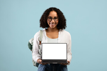 Portrait of young black female student holding laptop with blank screen for advertising website mockup