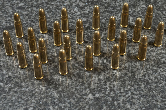 many Tokarev pistol cartridges (7.62×25mm) standing on a gray granite background