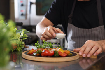 Professional chef putting bowl of sauce to delicious cooked dish in restaurant kitchen, closeup