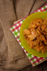 Green plate on burlap with stewed sweet potatoes or yam. Tasty nutricious dish, healthy vegan country food. Top view.