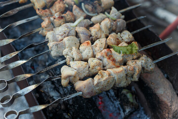 Raw marinaded pork meat pieces on skewers frying over bonfire. Kebab or traditional shashlik cooking with lot of smoke.
