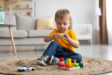 Child development games. Engaged toddler boy playing with wooden colorful stacking and sorting toy,...