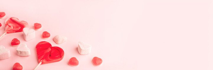 Pink romantic holiday banner with heart-shaped sweet candies. Decorative card for St. Valentine's Day with space for text.