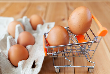 A few chicken eggs in the shopping basket next to cardboard bag, a chicken egg as a valuable nutritious product, a tray for carrying and storing fragile eggs. package of eggs, an important food item