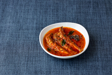 Top view of Sardine fish curry hot spicy Kerala masala fish curry for rice India Indian food red chili curry leaf Asian cuisine. Bengali Goan red fish curry coconut milk, mango clay pot Sri Lanka