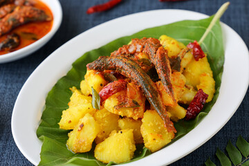 tapioca and spicy hot Kerala fish curry Indian food on banana leaf. Kappa sardine masala fish curry. Asian cuisine Bengali macher Jhal Goan fish curry in coconut milk cassava Sri Lanaka Tamil nadu