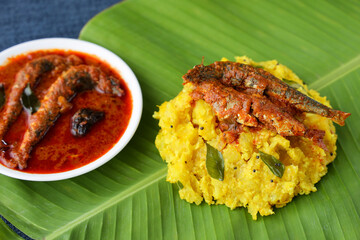 tapioca and spicy hot Kerala fish curry Indian food on banana leaf. Kappa sardine masala fish curry. Asian cuisine Bengali macher Jhal Goan fish curry in coconut milk cassava Sri Lanaka Tamil nadu