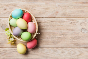 Obraz na płótnie Canvas Multi colors Easter eggs in the woven basket on colored background . Pastel color Easter eggs. holiday concept with copy space