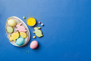 Colorful easter cookies in basket with Multi colors Easter eggs on colored background . Pastel color Easter eggs. holiday concept with copy space