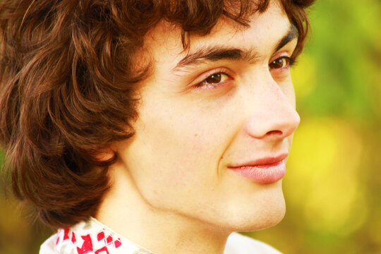 A young Slavic man in a national costume. Portrait of a classic Ukrainian or Belarusian, Lithuanian or Slaven. The shirt is embroidered. Curly dark hair.
