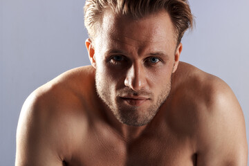 Fototapeta premium handsome sexy male model alone in the studio, a man with beautiful athletic muscles, jeans and a white t-shirt