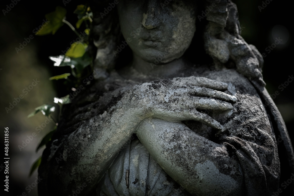 Wall mural praying angel folded arms across chest fragment of a very ancient stone statue.