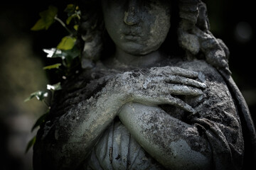 Praying angel folded arms across chest Fragment of a very ancient stone statue.