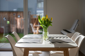 Spring photo of cozy home with yellow flowers on table and bright sunlight