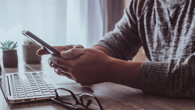 Hispanic man working from home and looking at his smart phone