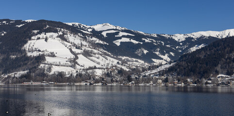 Blick über den See in verschneite Berge.