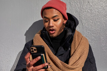 USA, New York City, Queer man in warm clothing looking at smart phone