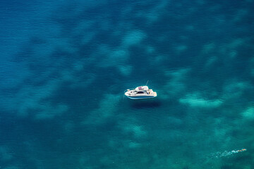 Leisure boat panoramic with swimmer on a turquoise calm sea. Elevated view of anchored small...