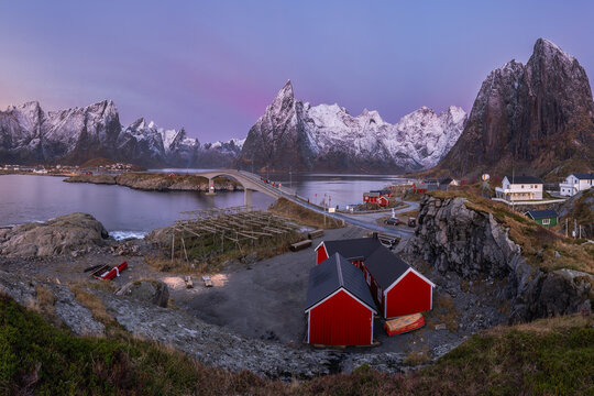 Small red cottages in valley near snowy mountains