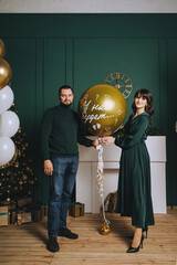 A stylish, bearded man and a cute, beautiful pregnant brunette girl are standing near a large...