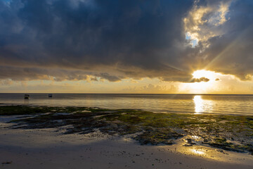 Panoramic view of the ocean. The sun shines through the clouds. The rays of the sun hit the sandy shore